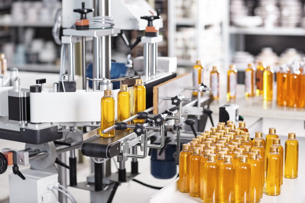 horizontal shot of cosmetics or pharmacy plant with automated equipment. transparent plastic bottles filled with yellow substance standing on desk and conveyor line, ready for transportation